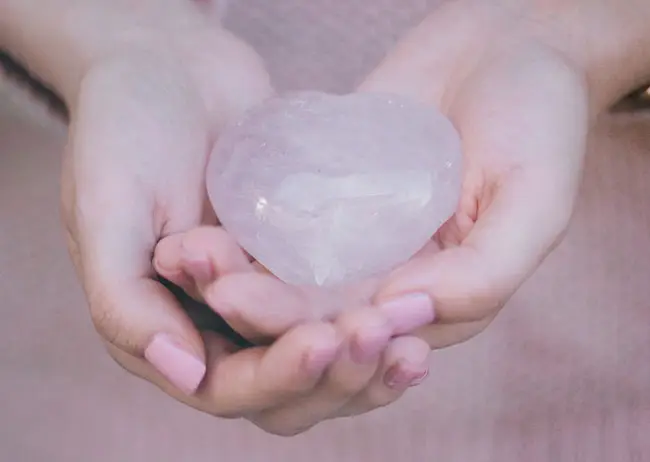 mani femminili che stringono un quarzo rosa