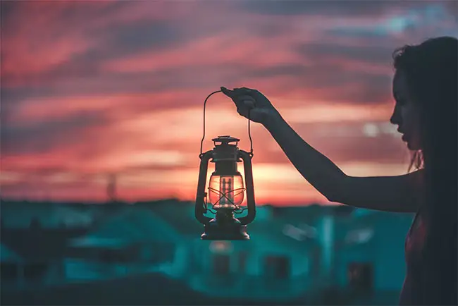 ragazza regge lanterna al tramonto