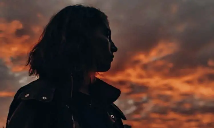 silhouette di donna che guarda il cielo nuvoloso al tramento