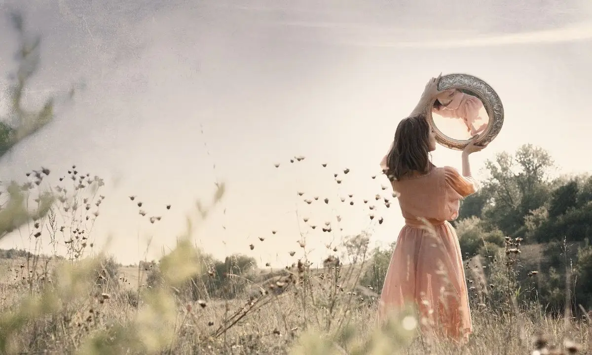 donna in mezzo a un campo con un cappello in mano