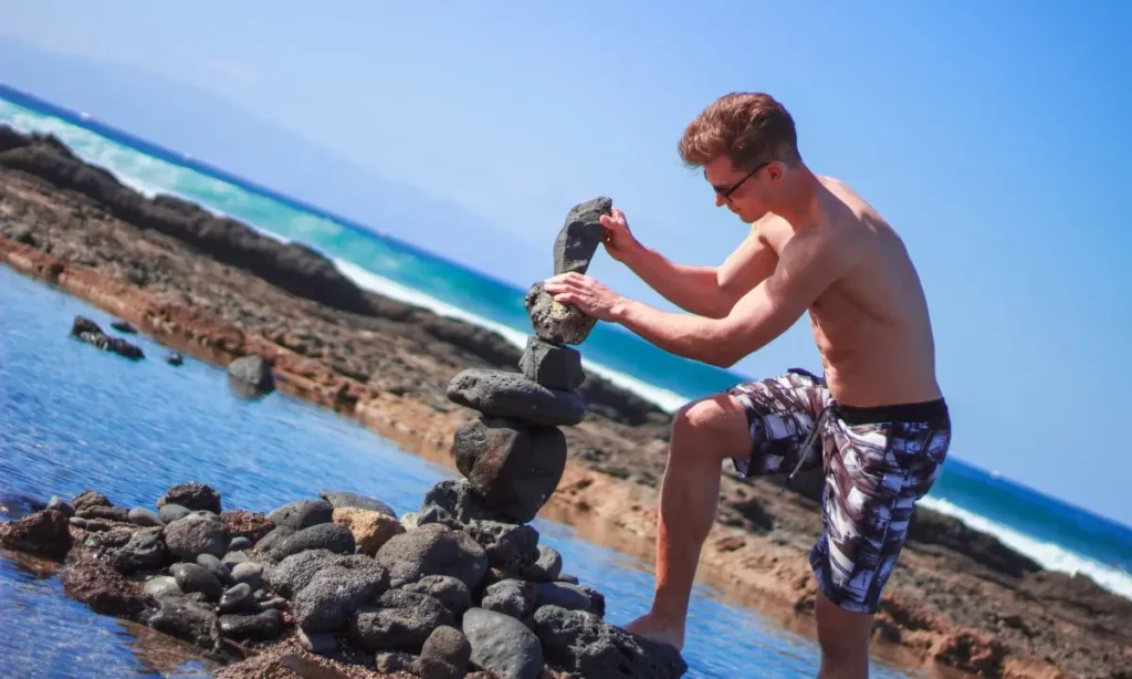 ragazzo impila pietre in spiaggia