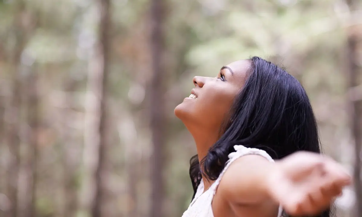 donna a braccia aperte nella natura guarda verso l'alto