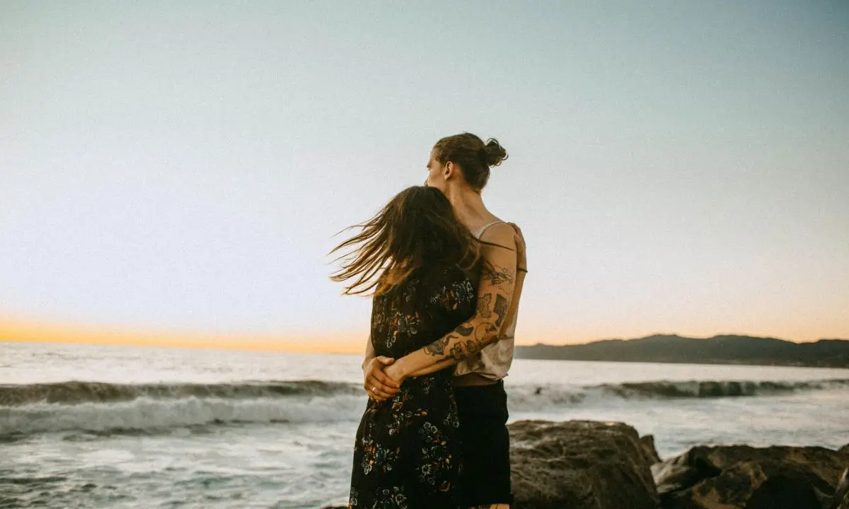 coppia si abbraccia in spiaggia