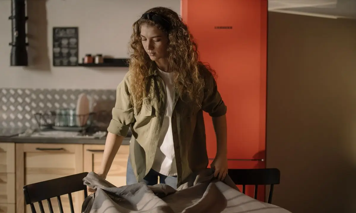 donna stende una tovaglia sul tavolo